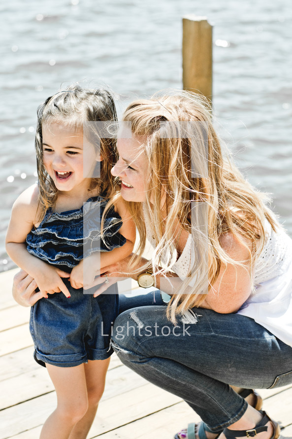 a mother standing with her daughter on a dock 