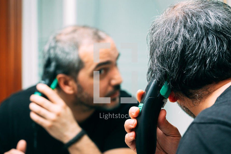 man cutting his hair with an electric razor