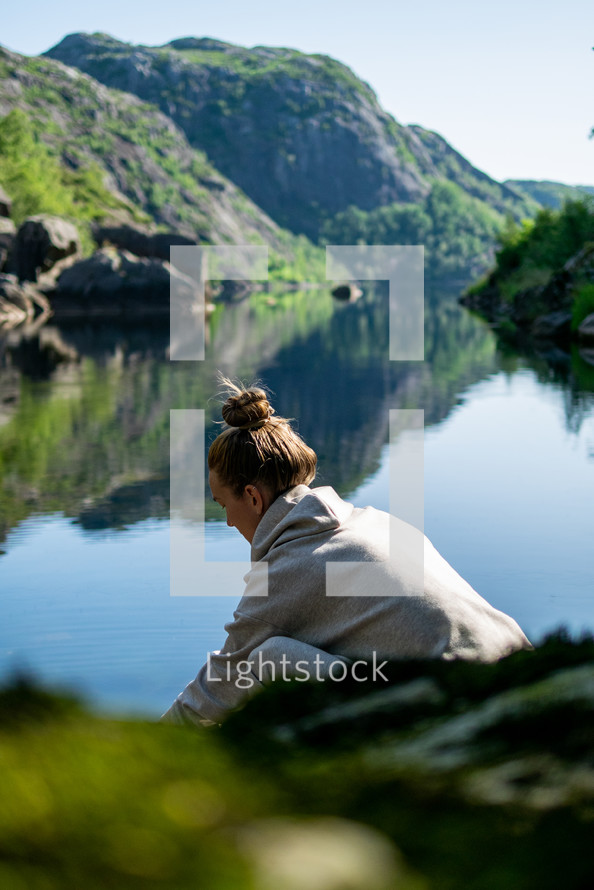 a woman sitting near a lake 