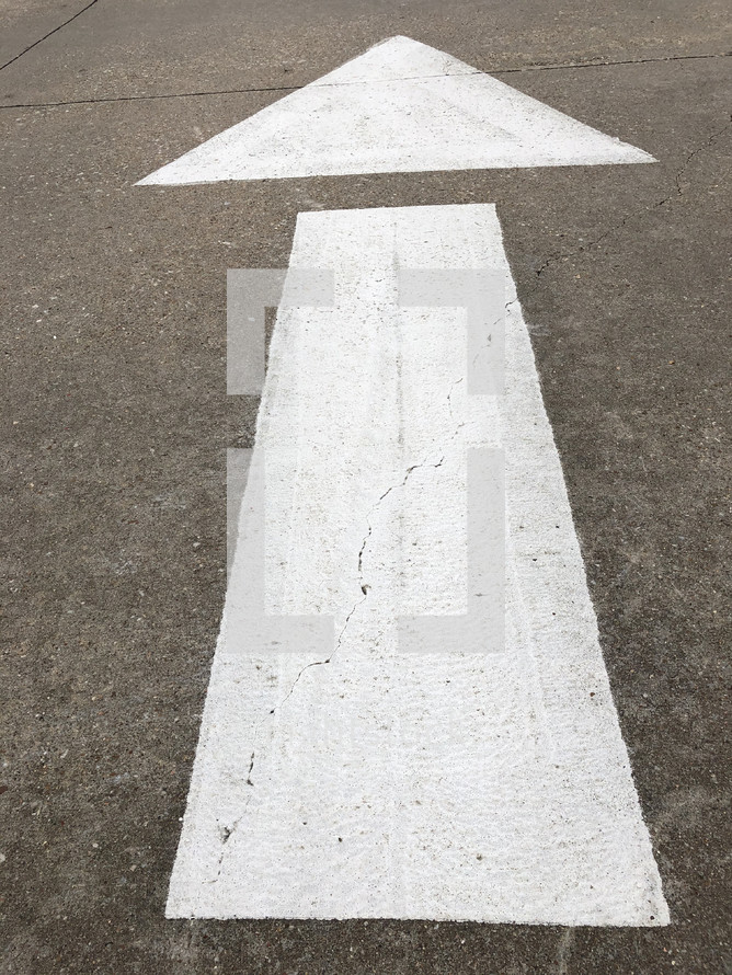 arrow painted with stencil on roadway, giving direction