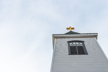 Looking up at church steeple with golden cross