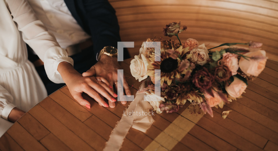 hands of a bride and groom on a table 