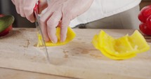 Slow motion close up of a chef knife slicing a yellow bell pepper