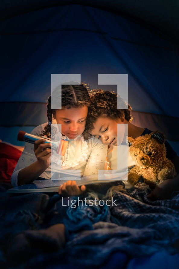 kids reading a book in a tent 