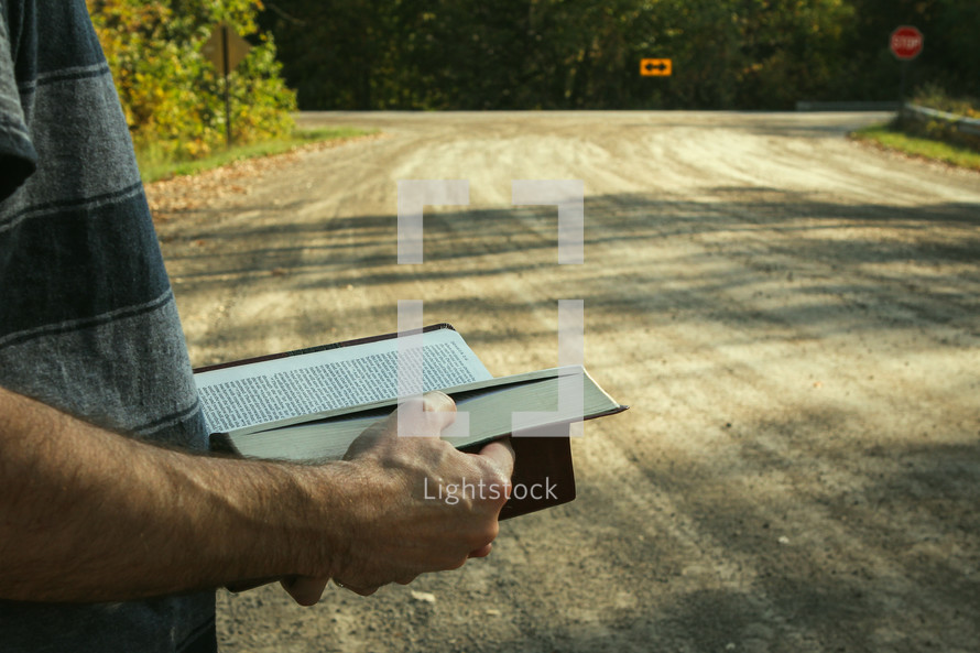 arrow street sign and a man reading a Bible 