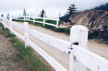 white fence along a dirt road 