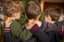 brothers hugging in front of a  Christmas tree 
