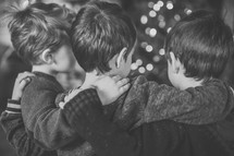 brothers hugging in front of a Christmas tree 