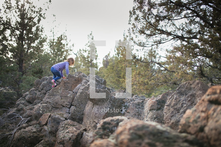 a girl child climbing rocks 