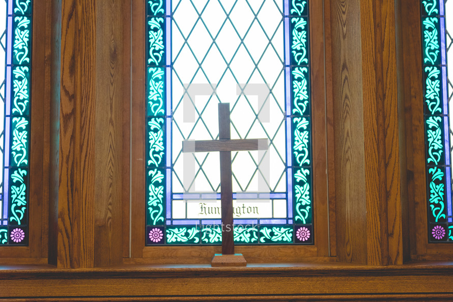 cross in front of a stained glass window 