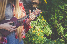 A young woman plays a ukulele.