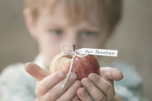 child holding an apple for the teacher 