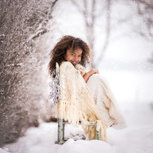 a little girl wrapped in a blanket in the snow 