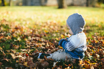 toddler boy playing in fall leaves