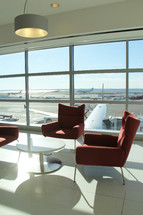 table and chairs and a view of the tarmac in an airport 