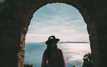 a woman in a hat standing under an arch in Peru 