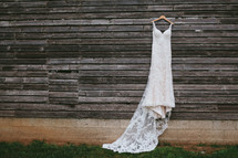 wedding dress hanging on weathered wood siding 
