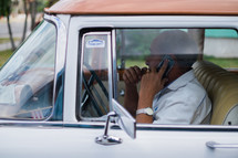 a man talking on a cellphone in a vintage car in Havana, Cuba 