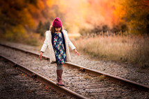a little girl balancing on train tracks 