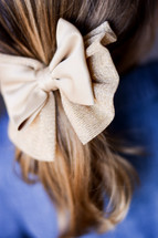 a tan bow in a girls pony tail 