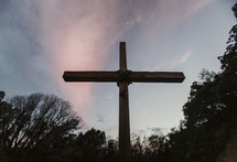 A large wooden cross rises toward the sky.