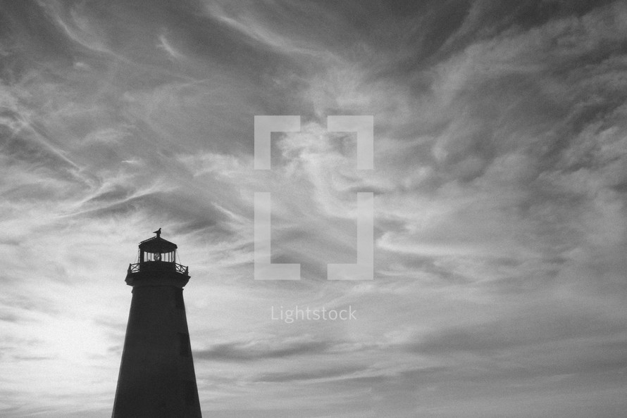 silhouette of a lighthouse under a cloudy sky