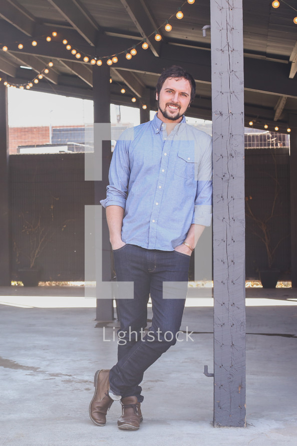 man leaning against a pole outdoors 