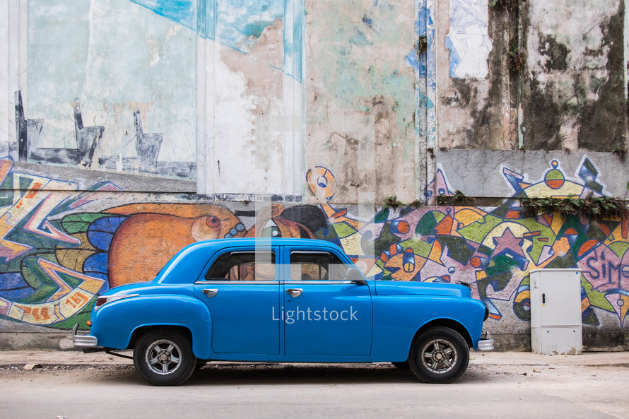 vintage car and graffiti covered wall in Havana, Cuba 