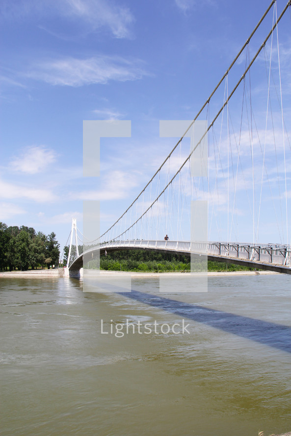 a man walking across a bridge over a river 