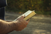 a man holding a Bible outdoors
