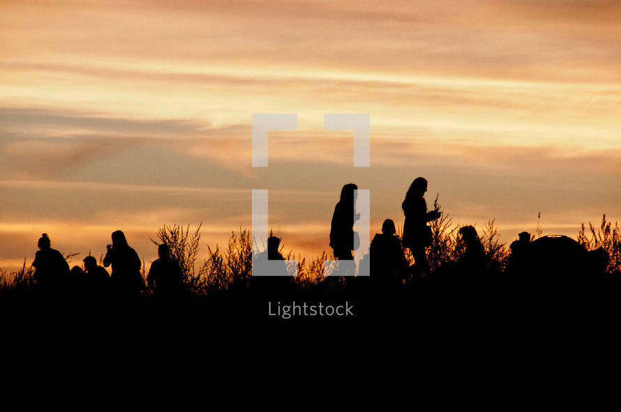 group of people standing outdoor at sunset 