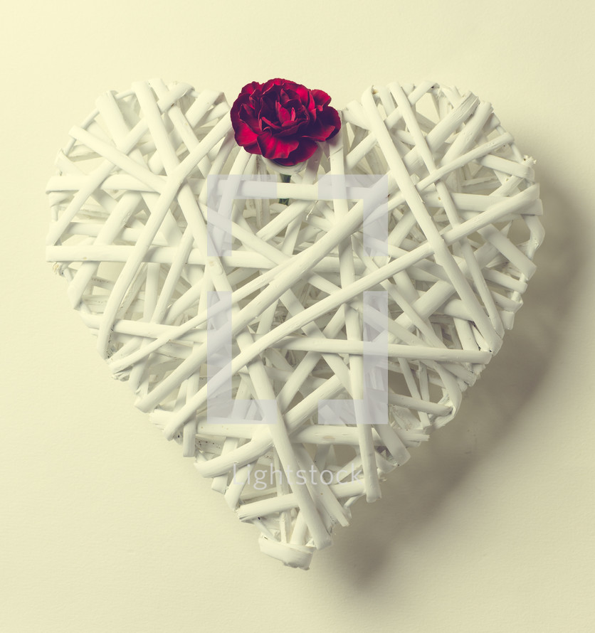 A white heart made of twigs with a red flower.