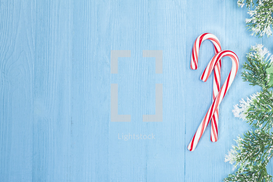 candy canes and Christmas greenery on blue 