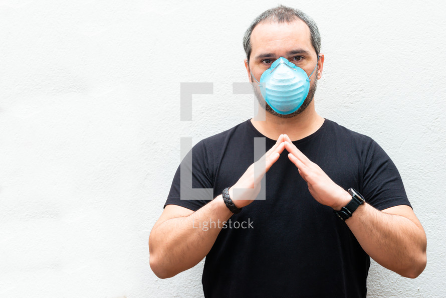 Man with medical mask holds hands over a house. Concept of home stay, quarantine.
