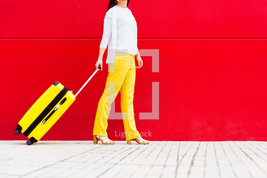 woman with a yellow suitcase walking down the street.
