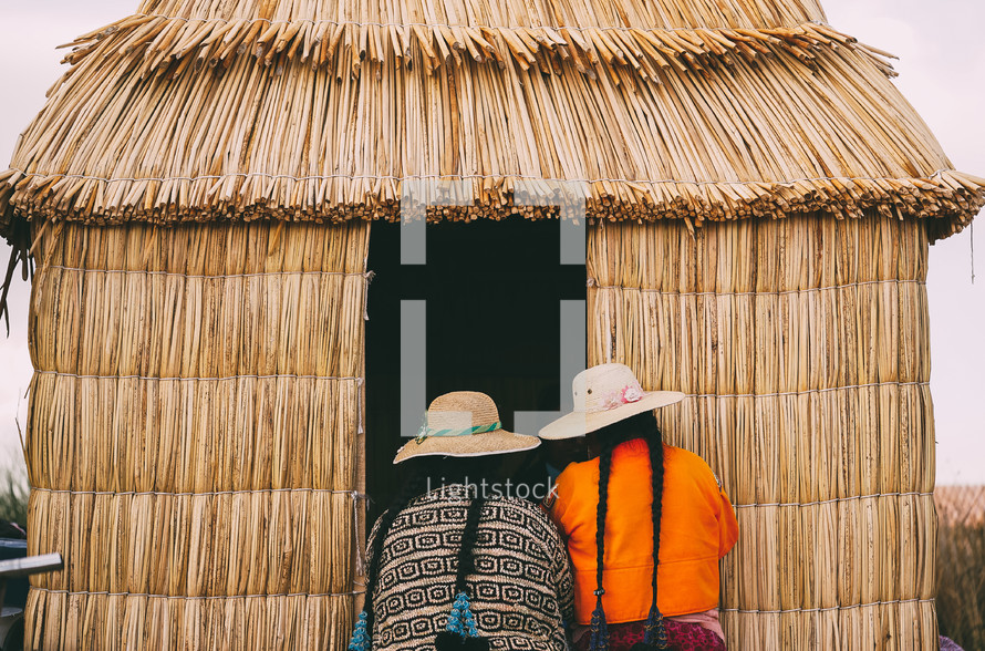 women at the entrance of a straw hut in Peru 