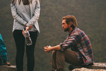 a man sitting on a mountaintop near friends praying 