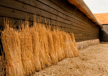 Bales of straw leaning against a barn.