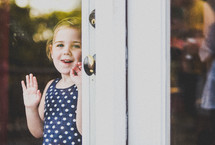 toddler girl looking out a glass door 