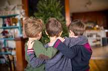 brothers hugging in front of a Christmas tree