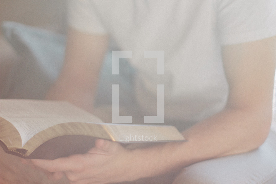 torso of a teen boy reading a Bible 