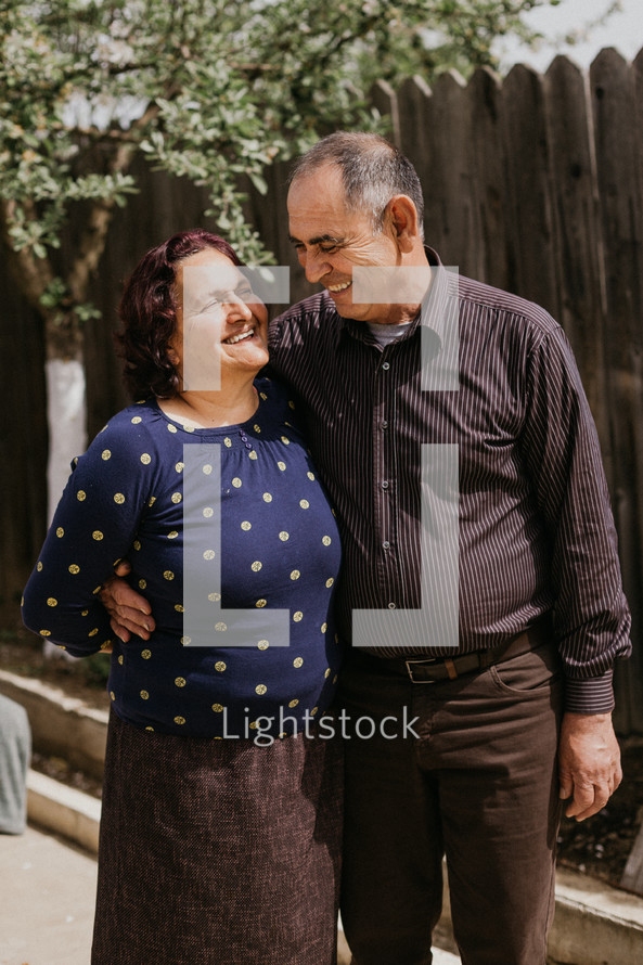 smiling older couple by a fence