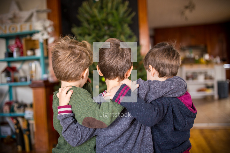 brothers hugging in front of a Christmas tree