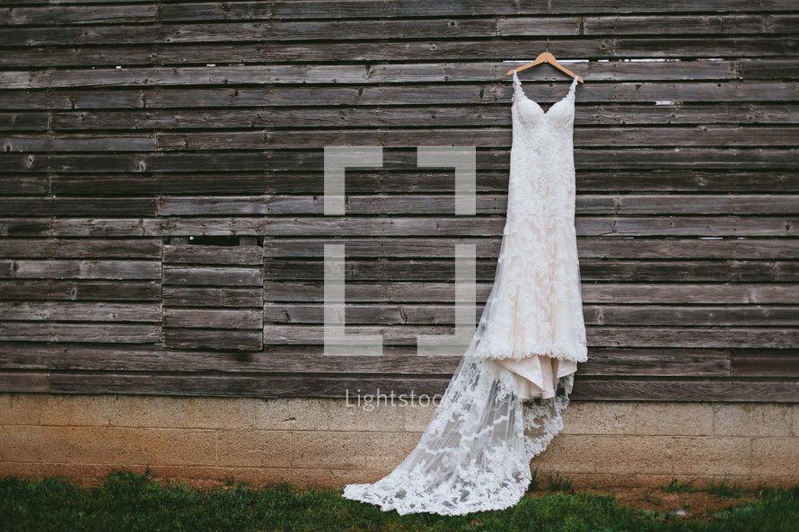 wedding dress hanging on weathered wood siding 
