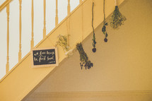 A Bible verse and dried flowers hanging from a staircase.