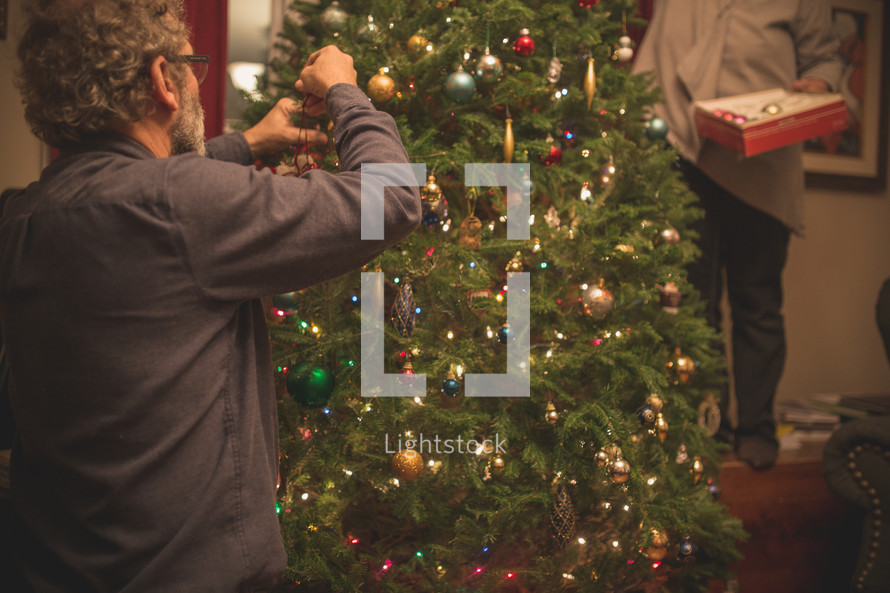 a man decorating a Christmas tree 