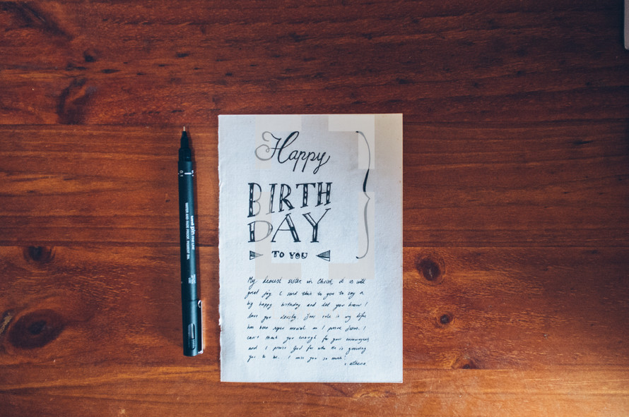 Handmade birthday card and pen on a wooden table.