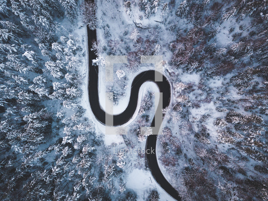 aerial view over a curvy road and snow on trees