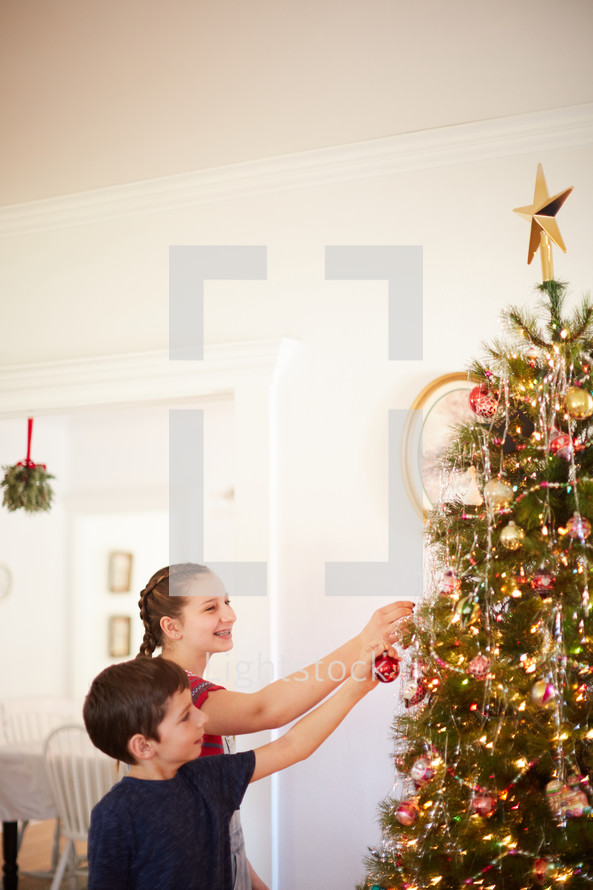 children decorating a Christmas tree together