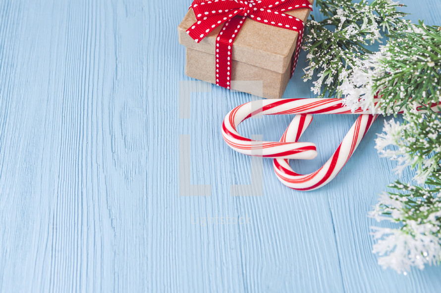 candy canes, gift box, and Christmas greenery on blue 